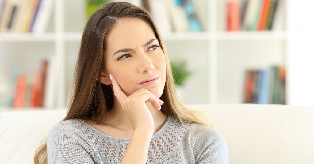 Front view portrait of a woman wondering sitting on a sofa at home
